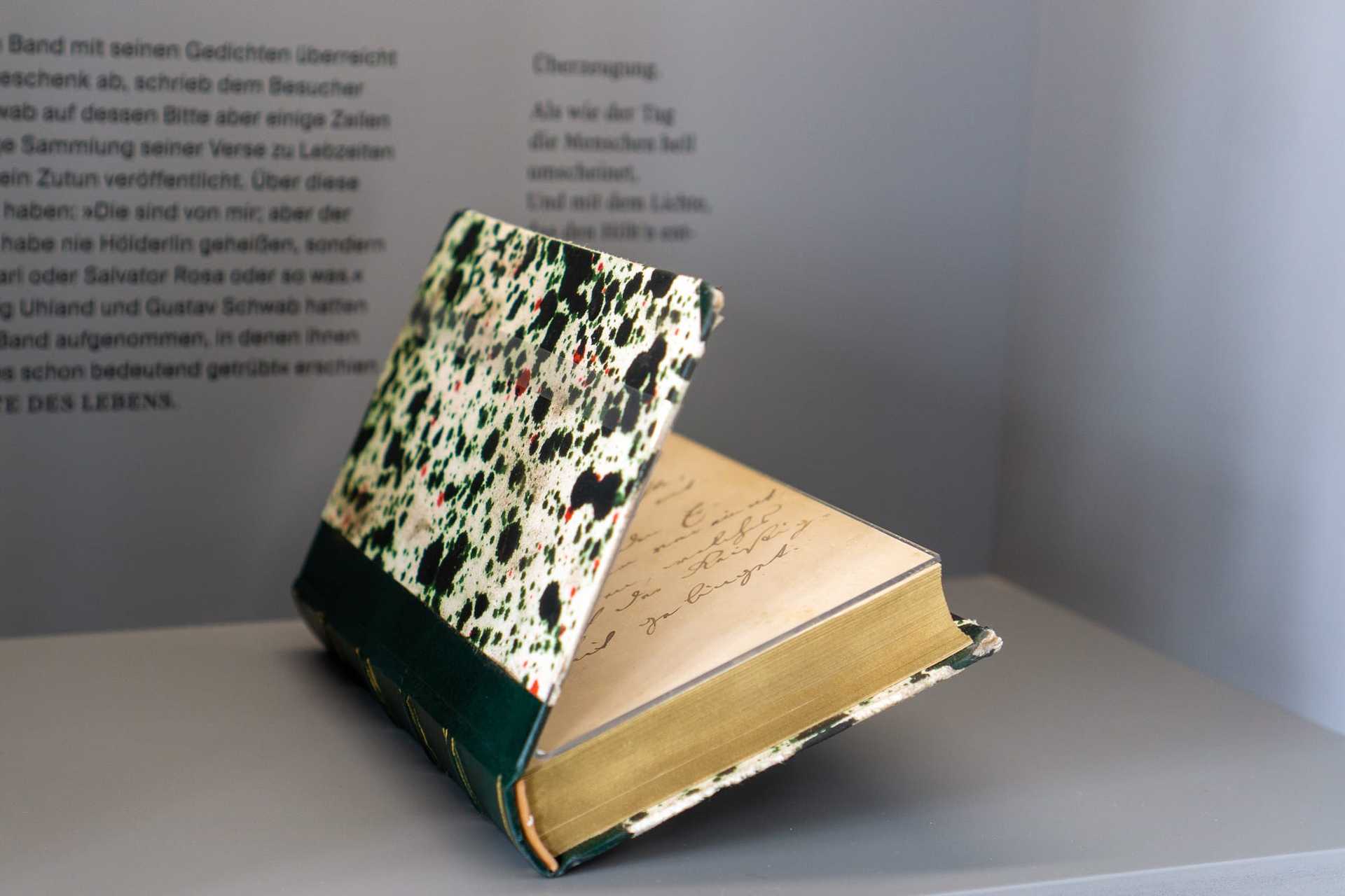 Aufgeklapptes Buch mit marmoriertem Einband in einer Vitrine
